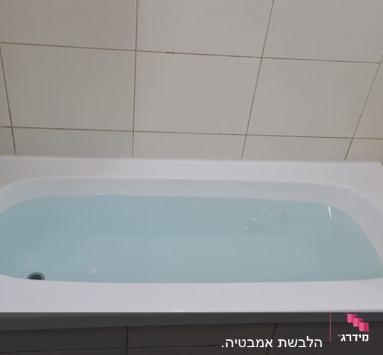 אמבטיה עם מים, ברז וכיסוי אריחים לבנים